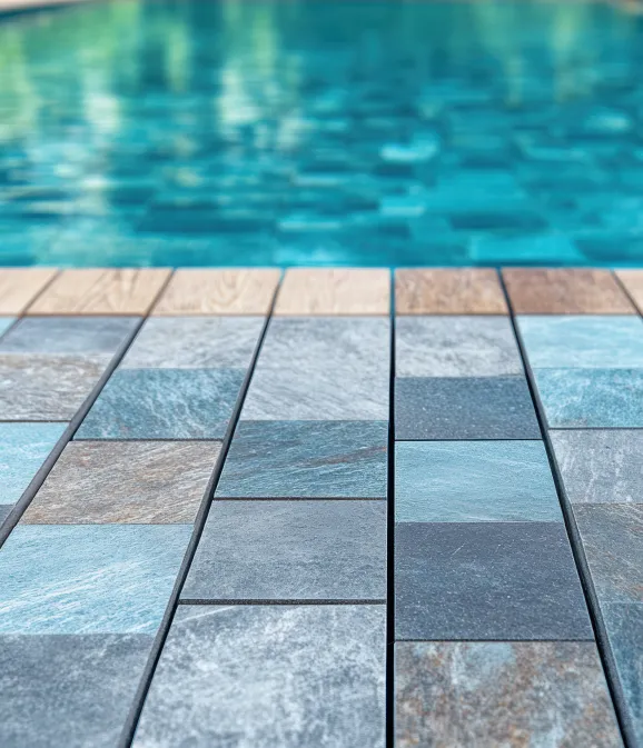 Low-angle view of textured slate pool coping tiles leading up to clear turquoise swimming pool water.